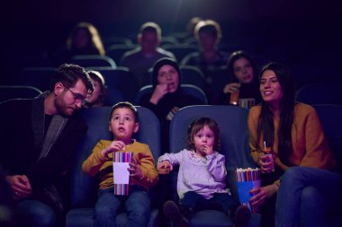 Modern bir aile, çocuklarıyla film izlerken patlamış mısırın tadını çıkarır..