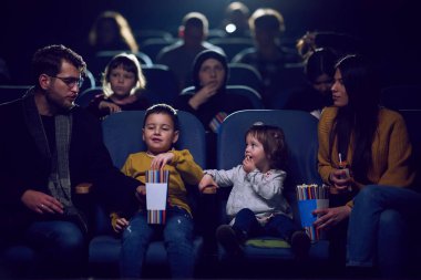 Modern bir aile, çocuklarıyla film izlerken patlamış mısırın tadını çıkarır..