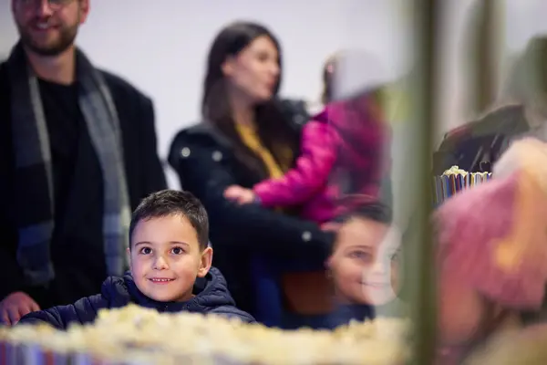 stock image A young couple with their children stands outside the cinema, purchasing freshly popped popcorn before the start of the movie and entry into the theater.