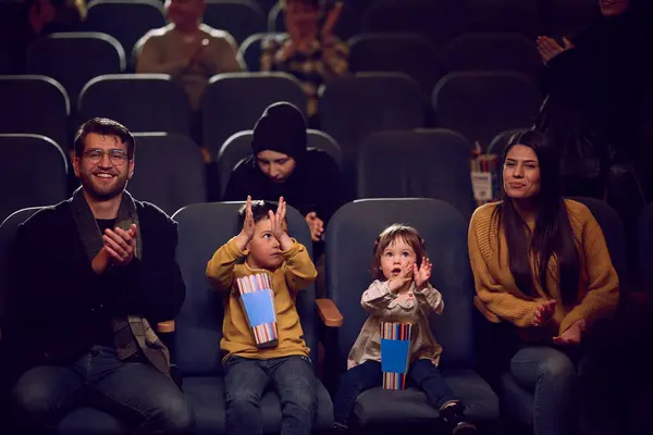stock image A modern family enjoys quality time together at the cinema, indulging in popcorn while watching a movie with their children.