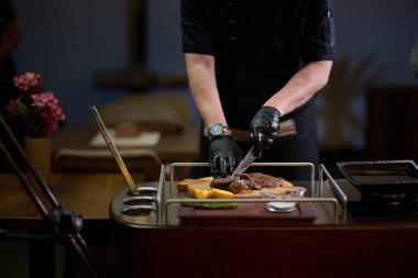 Yakın çekim, profesyonel bir şef modern aşçılık teknikleri, mutfak mükemmelliği ve gurme mutfağı sanatında ustalıkla lezzetli bir biftek hazırlar..