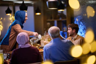 Çağdaş bir restoranda iftar için bir araya gelen modern ve geleneksel Avrupalı İslami aile, Ramazan ayında kültürel uyum ve aile birliğini somutlaştırıyor.