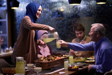 Çağdaş bir restoranda iftar için bir araya gelen modern ve geleneksel Avrupalı İslami aile, Ramazan ayında kültürel uyum ve aile birliğini somutlaştırıyor.