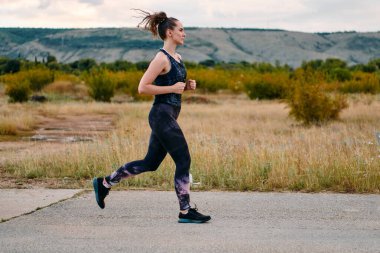 Kararlı bir sporcu güneşin altında kendinden emin bir şekilde koşar. Çevresi göz kamaştırıcı doğal manzaralarla çevrilidir. Zindelik arayışında güç ve direnç gösterir. 