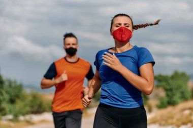 Sabah doğada koşan koruyucu maskeler takan bir çift.. 
