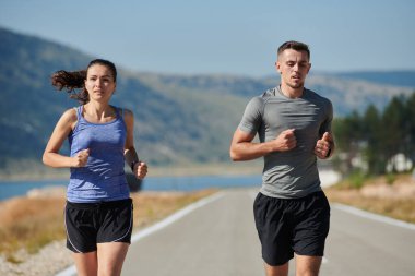 Bir çift güneş lekeli bir yolda koşar, vücutları güçlü ve sağlıklıdır, birbirlerine olan sevgileri ve her adımda aşikardır.. 