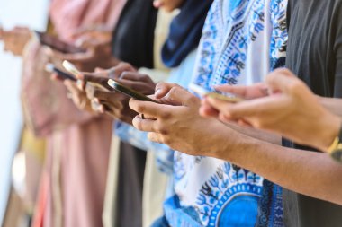 Çeşitli gençlerden oluşan bir grup, akıllı telefonlarına dalmış, modern bağlantılarını ve sosyal etkileşimlerini sergiliyorlar..