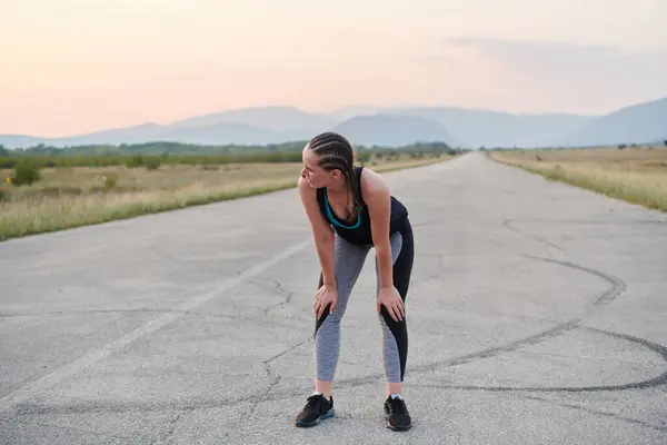 stock image A close-up captures the raw dedication of a female athlete as she rests, sweat glistening, after a rigorous running session, embodying the true spirit of perseverance and commitment to her fitness