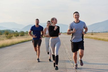 Bir grup arkadaş, güneşli bir günde dışarıda koşuşturarak sağlıklı bir yaşam tarzını sürdürüyor. Spor ve doğanın enerji verici etkilerinden keyif alıyorlar.. 