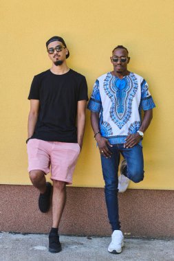 Afro-Amerikan bir gencin çarpıcı sarı arka planda geleneksel Sudan kıyafetleri giymiş canlı bir portresi.. 
