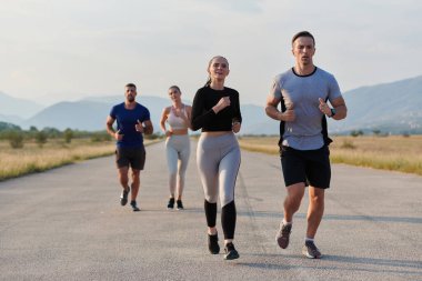 Bir grup arkadaş, güneşli bir günde dışarıda koşuşturarak sağlıklı bir yaşam tarzını sürdürüyor. Spor ve doğanın enerji verici etkilerinden keyif alıyorlar.. 