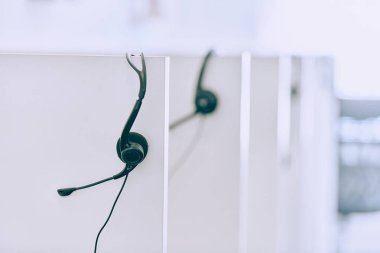 Samimi bir yakın çekim çağrı merkezinde yeni bir iş günü beklentisini yakalar, düzgün düzenlenmiş kulaklıklar kusursuz iletişim ve özel müşteri hizmetleri için hazırlığı simgeler.