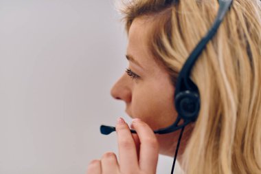 Dost canlısı çağrı merkezi ajanı gelen aramalara kulaklıkla cevap veriyor, müşteri hizmetlerini uzaktan sağlıyor. Müşteri sorunlarını çözmek için mükemmel iletişim yeteneklerini kullanan mutlu bir kadın.. 