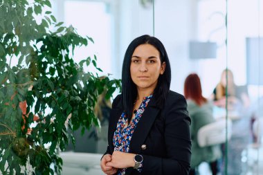 Çapraz kollu bir iş kadını, ofis ortamında kendine güven ve otorite yayıyor..