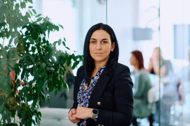 Çapraz kollu bir iş kadını, ofis ortamında kendine güven ve otorite yayıyor..