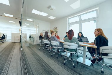 Çeşitli iş adamları modern cam duvarlı bir ofisteki projeler hakkında tartışmaya giriştiler.. 