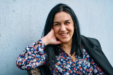 Başarılı bir siyahi iş kadını, arka planında çarpıcı mavi bir duvar bulunan sakin bir şehir manzarasına tepeden bakan şirketinin terasında düşünceli bir şekilde oturur..