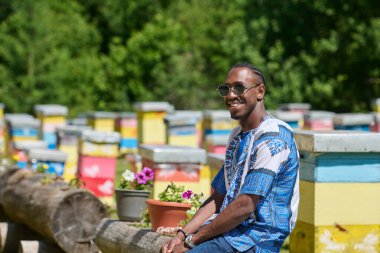  African American teenager clad in traditional Sudanese attire explores small beekeeping businesses amidst the beauty of nature clipart