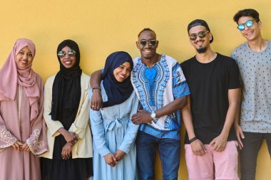 Afro-Amerikan ve Ortadoğu gençlerinden oluşan çeşitli bir grup canlı sarı bir duvarın önünde güvenle duruyor, birlik ve kentsel tarzı sergiliyorlar.