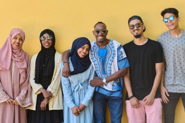 Afro-Amerikan ve Ortadoğu gençlerinden oluşan çeşitli bir grup canlı sarı bir duvarın önünde güvenle duruyor, birlik ve kentsel tarzı sergiliyorlar.