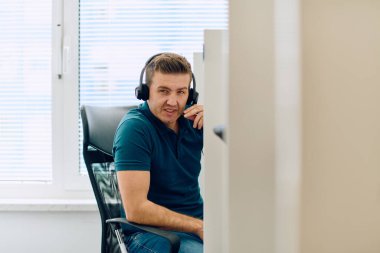 Detaylı bir yakın çekim, çağrı merkezi ortamında yardım sağlarken odaklanmış bir müşteri destek temsilcisini kulaklık takarken yakalar. 