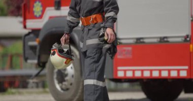 İtfaiye arabasının yanında duran özel bir itfaiye eri tehlikeli yangın senaryolarında yüksek riskli bir kurtarma görevine hazırlanıyor. Acil durumlarda hayat kurtarmaya kararlı olduğunu gösteriyor.