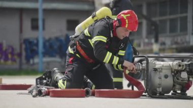 İtfaiyecilerden oluşan özel bir ekip bir itfaiye aracından hortumları alıyor ve tehlikeli bir tehlikeyle mücadele etmedeki cesaret ve profesyonel uzmanlıklarını sergileyerek, yanan bir yangını söndürmek için tehlikeli bir göreve çıkıyorlar.