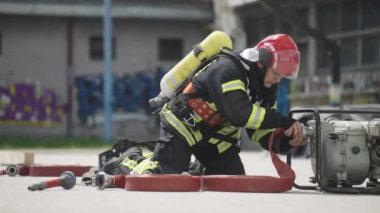İtfaiyecilerden oluşan özel bir ekip bir itfaiye aracından hortumları alıyor ve tehlikeli bir tehlikeyle mücadele etmedeki cesaret ve profesyonel uzmanlıklarını sergileyerek, yanan bir yangını söndürmek için tehlikeli bir göreve çıkıyorlar.