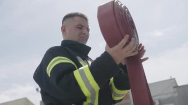 Profesyonel bir itfaiyeci, tehlikeli bir operasyondan sonra yangın hortumlarını titizlikle temizleyip depoluyor ve bu da ameliyat sonrası bakım ve güvenlik protokollerinin önemini gösteriyor.