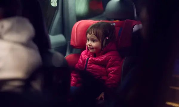 stock image A young girl sits comfortably in a modern car seat, secured and ready for a family adventure on the road