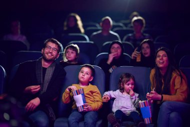 Modern bir aile, çocuklarıyla film izlerken patlamış mısırın tadını çıkarır..