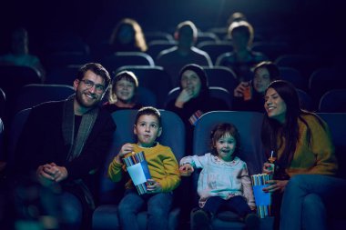 Modern bir aile, çocuklarıyla film izlerken patlamış mısırın tadını çıkarır..