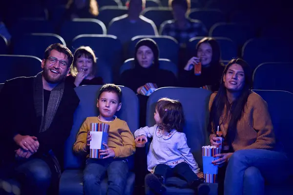 stock image A modern family enjoys quality time together at the cinema, indulging in popcorn while watching a movie with their children.