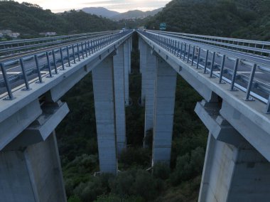 İtalyan dağındaki karayolu köprüsünde hava manzarası. Güzel günbatımı ve arka planda ünlü İtalyan sahili. Sinematik Drone bakış açısı ulaşım konsepti. Çekim ayarlanıyor.