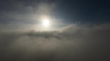 Dağlarda taze bir sabahta inanılmaz güzel bir bulutun içinden uçmak. Beyaz tüylü bulutlardan oluşan FPV insansız hava aracı açık mavi gökyüzünde usulca hareket ediyor