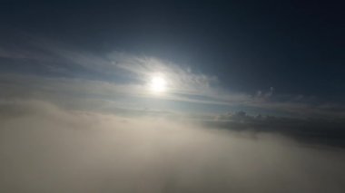 Dağlarda taze bir sabahta inanılmaz güzel bir bulutun içinden uçmak. Beyaz tüylü bulutlardan oluşan FPV insansız hava aracı açık mavi gökyüzünde usulca hareket ediyor