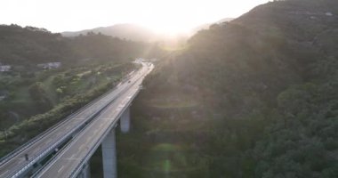 İtalyan dağındaki karayolu köprüsünde hava manzarası. Güzel günbatımı ve arka planda ünlü İtalyan sahili. Sinematik Drone bakış açısı ulaşım konsepti. Çekim ayarlanıyor.