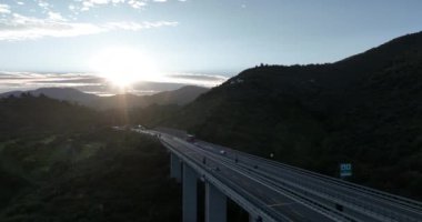 İtalyan dağındaki karayolu köprüsünde hava manzarası. Güzel günbatımı ve arka planda ünlü İtalyan sahili. Sinematik Drone bakış açısı ulaşım konsepti. Çekim ayarlanıyor.