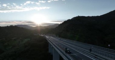 İtalyan dağındaki karayolu köprüsünde hava manzarası. Güzel günbatımı ve arka planda ünlü İtalyan sahili. Sinematik Drone bakış açısı ulaşım konsepti. Çekim ayarlanıyor.