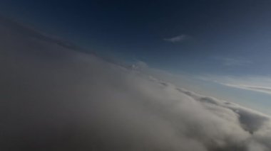 Dağlarda taze bir sabahta inanılmaz güzel bir bulutun içinden uçmak. Beyaz tüylü bulutlardan oluşan FPV insansız hava aracı açık mavi gökyüzünde usulca hareket ediyor