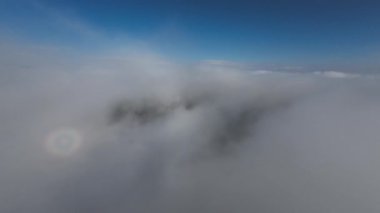 Dağlarda taze bir sabahta inanılmaz güzel bir bulutun içinden uçmak. Beyaz tüylü bulutlardan oluşan FPV insansız hava aracı açık mavi gökyüzünde usulca hareket ediyor