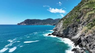 Engebeli, kayalık kıyı şeridini yıkayan turkuaz okyanus sularının hava görüntüleri. Deniz dalgaları kıyıya vuruyor. Yukarıdan görünüyor. Yüksek kalite sinematik yavaş çekim görüntüleri.