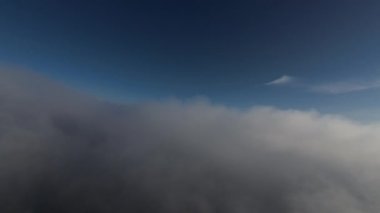 Taze bir yaz sabahı dağlarda muhteşem bir bulutlar arasında uçmak. Beyaz tüylü bulutlardan oluşan FPV insansız hava aracı açık mavi gökyüzünde usulca hareket ediyor