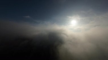 Taze bir yaz sabahı dağlarda muhteşem bir bulutlar arasında uçmak. Beyaz tüylü bulutlardan oluşan FPV insansız hava aracı açık mavi gökyüzünde usulca hareket ediyor