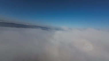 Taze bir yaz sabahı dağlarda muhteşem bir bulutlar arasında uçmak. Beyaz tüylü bulutlardan oluşan FPV insansız hava aracı açık mavi gökyüzünde usulca hareket ediyor