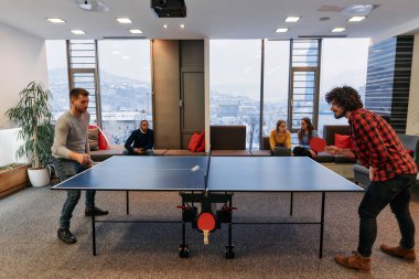  İş arkadaşları masa tenisi oynamak, iş yerinde takım çalışması ve arkadaşlığı teşvik etmek için işe ara veriyorlar.. 