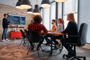 Kurumsal bir ortamda, Afrikalı-Amerikalı bir işadamı bir toplantıya liderlik eder, özenli ekibine tutkuyla bir iş planı sunar, işbirliği ve stratejik düşünmeyi teşvik eder.. 