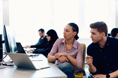 Ofiste yapılan beyin fırtınası sırasında çok kültürlü genç iş adamlarının ortak çalışma süreci. Resmi olarak giyinmiş çeşitli gençler tasarım projesinin geliştirilmesinde işbirliği yapıyor.