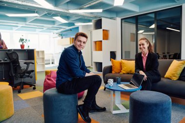 Çok ırklı bir girişim ekibi modern, açık alan çalışma ofisinde toplanıyor. Beyin fırtınası, dizüstü bilgisayarda çalışmak. Hareket bulanıklığı içinde dolaşan bir grup iş arkadaşı.