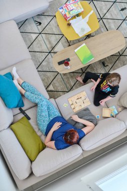 Bir anne ve kızın evdeki koltukta oturup eğlenceli ve büyüleyici bir masa oyunu oynamalarının iç açıcı görüntüsü..